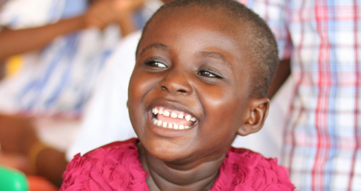 Sorriso de criança beneficiada por projetos sociais, resultado do impacto positivo em comunidades.