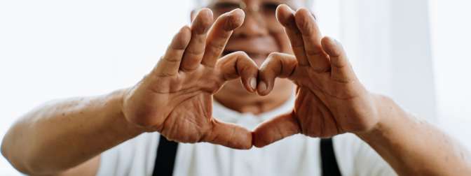 Idoso formando um coração com as mãos, simbolizando cuidado, empatia e acessibilidade residencial para idosos